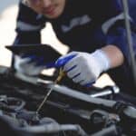 Auto mechanic is working on car engine in mechanic shop. A mechanic in uniform is working on a car service. Work in repair shops and maintenance services.