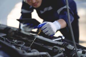 Auto mechanic is working on car engine in mechanic shop. A mechanic in uniform is working on a car service. Work in repair shops and maintenance services.