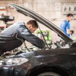 Car master auto mechanic repairer service technician checks and repairs the engine condition under the hood of the vehicle service shop